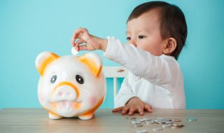 little baby moneybox putting a coin into a piggy bank - kid saving money for future concept