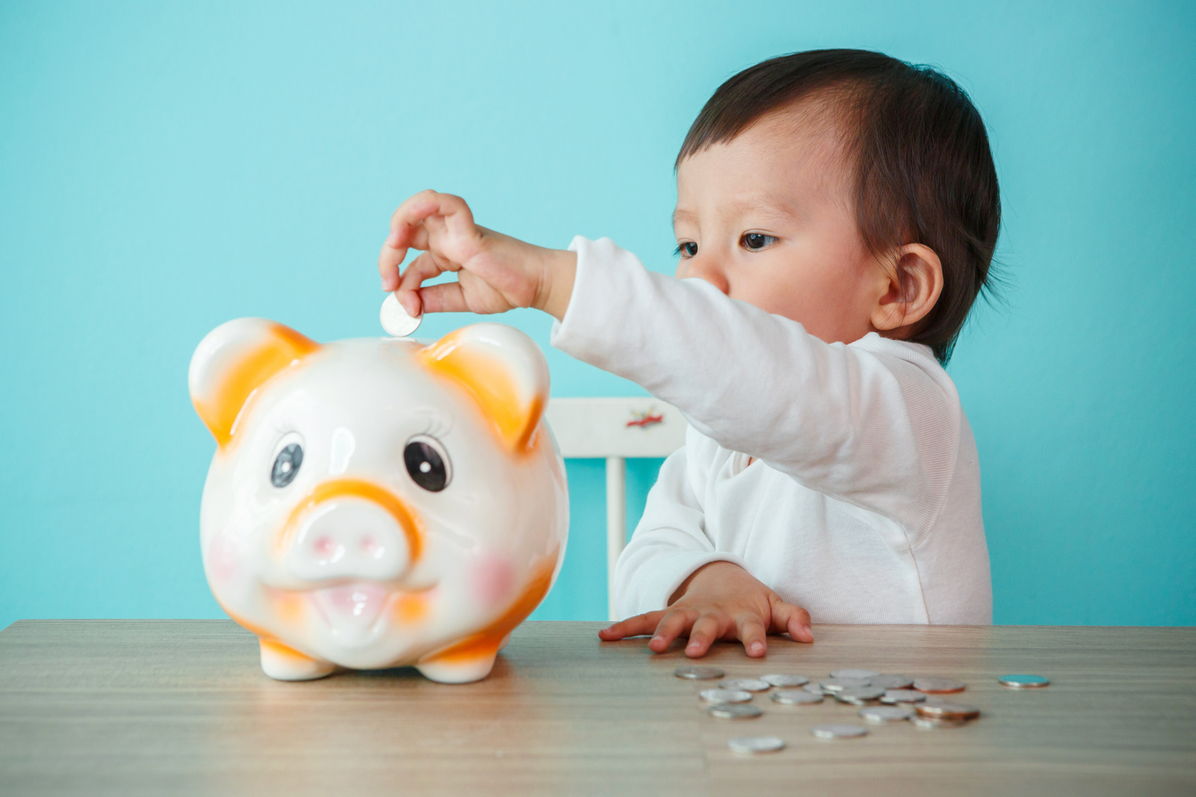 little baby moneybox putting a coin into a piggy bank - kid saving money for future concept
